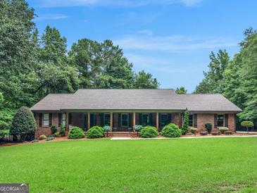 Charming brick home with a welcoming front porch, lush lawn, and mature landscaping at 230 Shorewood Ct, Mcdonough, GA 30252