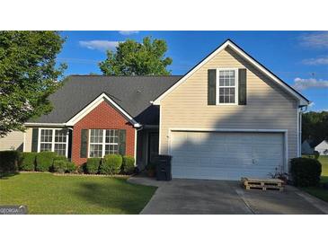 Charming home showcasing a manicured lawn, a two-car garage, and traditional siding at 1525 Racquet Club Dr, Lawrenceville, GA 30043