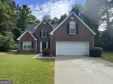 Charming brick home with a two-car garage and well-manicured lawn at 4551 Mitchells Meadow Ln, Ellenwood, GA 30294