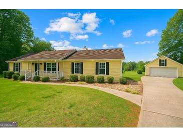 Charming yellow house with black shutters, manicured front lawn, and detached two-car garage at 183 Brookwood Estates Trl, Stockbridge, GA 30281