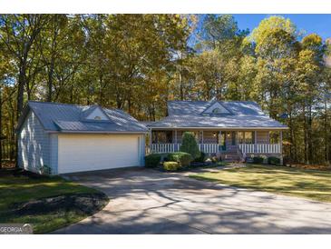 Charming home with a welcoming front porch and a detached garage surrounded by lush trees at 335 Gum Creek Rd, Roopville, GA 30170