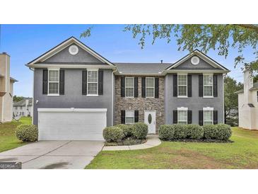 Charming two-story home featuring a stone facade, gray siding, black shutters and a well-manicured lawn at 122 Claxton Ct, Jonesboro, GA 30238