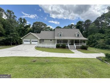 Charming home featuring a welcoming front porch and a spacious driveway, surrounded by lush trees and a well-manicured lawn at 3133 Callie Still Rd., Lawrenceville, GA 30045