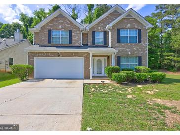 Two-story brick home featuring a two-car garage, white trim, and landscaped front yard at 325 Espana St, South Fulton, GA 30349