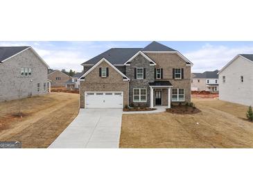 Two-story home with a brick and stone facade, two-car garage, and well-maintained lawn at 1804 Quaker St, Hampton, GA 30228