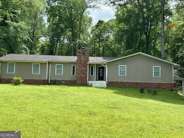 Charming single-story home with a brick chimney and neutral siding, nestled in a wooded area at 142 Carrollwood Dr, Fayetteville, GA 30215