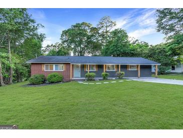 Charming single-story home featuring a brick and gray facade, complemented by a lush green lawn and mature trees at 1091 Pine St, Conyers, GA 30012