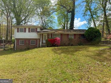 Charming split-level home with brick facade, red shutters, and colorful landscaping on a lush green lawn at 5637 Sturbridge Way, South Fulton, GA 30349
