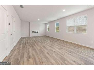Spacious living room featuring hardwood floors, a fireplace, and ample natural light from large windows at 8501 Polston Pl # 143, Douglasville, GA 30134