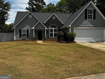 Charming single Gathering home with stone accents, gray siding, a well-manicured lawn, and a two car garage at 556 Walton Dr, Social Circle, GA 30025