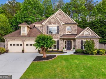 Charming two-story brick home featuring a manicured lawn, three-car garage, and professionally landscaped yard at 3707 Lance Bluff Ln, Duluth, GA 30097