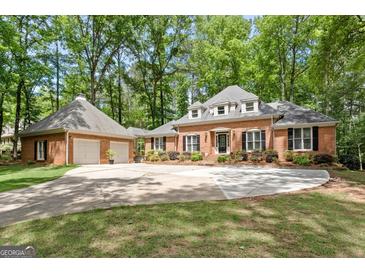 Stunning brick home with a well-manicured lawn and a long driveway leading to an attached two car garage at 145 Oxford Ln, Fayetteville, GA 30215