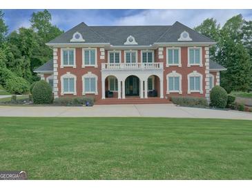 Stately brick home with a manicured lawn and grand entrance featuring a balcony and columns at 205 Somerset Ct, Mcdonough, GA 30253