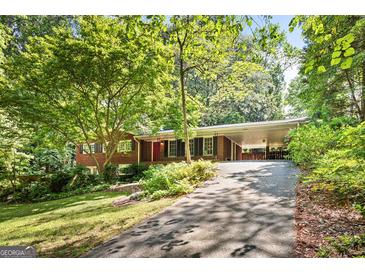 Charming brick home with a red front door and a covered carport surrounded by lush greenery at 3571 Lake Se Dr, Smyrna, GA 30082