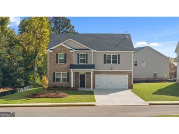 Charming two-story home featuring a combination of brick and siding, a two-car garage, and a well-manicured front lawn at 1940 Van Allen Ct # 12, Dacula, GA 30019