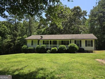 Charming home featuring a covered porch, a well-manicured lawn, and lovely landscaping at 220 Jackson Rd, Mcdonough, GA 30252