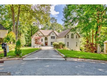 Stately two-story home boasts a sprawling driveway, lush landscaping, and a tranquil wooded setting at 1214 Weatherstone Way, Peachtree City, GA 30269