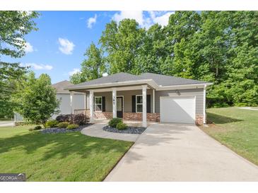 Charming single-story home featuring a welcoming front porch, well-manicured lawn, and attached one car garage at 385 Orchard Land, Covington, GA 30014