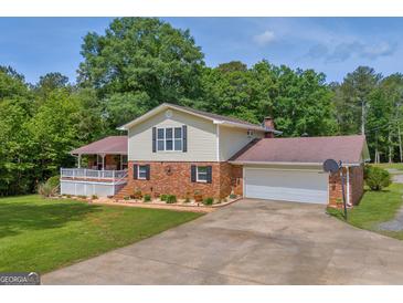 Two-story home with a brick and vinyl exterior, attached garage, long driveway, and manicured lawn at 6023 Highway 20 S, Covington, GA 30016