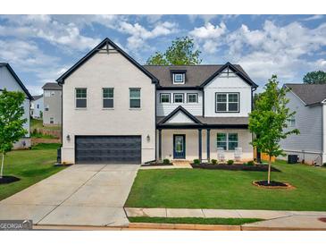 Beautiful two-story home with white brick, black trim, attached garage, and well-maintained front yard at 5350 Woodline View Cir, Hoschton, GA 30548