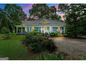 Charming blue home with a covered porch, lush landscaping, and a welcoming gravel driveway at 7550 Fielder Rd, Jonesboro, GA 30236