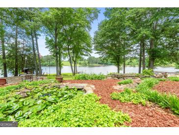 Lush backyard featuring a pond and landscaping with water views of the lake at 312 Flat Shoals Church Rd, Stockbridge, GA 30281