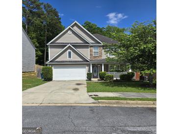 Charming two-story home featuring a two-car garage and inviting front porch nestled among mature trees at 590 Dot Dr, Atlanta, GA 30349