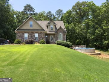 Charming two-story home featuring stone accents, a well-manicured lawn, and an inviting above ground pool at 200 Scouts Ridge Dr, Covington, GA 30016