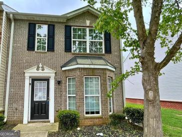 Charming brick townhome featuring black shutters and a well-manicured front yard at 1843 Grove Way, Hampton, GA 30228