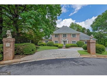 Stately brick home featuring a circular driveway, lush landscaping, and two decorative lion statues at the entrance at 2795 Hawthorne Dr, Atlanta, GA 30345