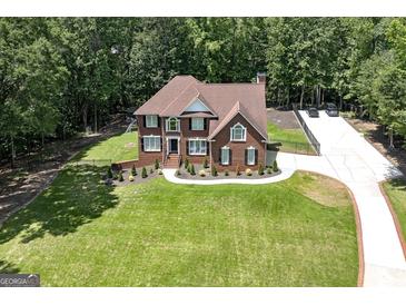 Beautiful brick home featuring a lush lawn, mature trees, and a long driveway at 20 Allie Dr, Mcdonough, GA 30252