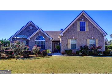 Charming brick home featuring a well-maintained lawn, mature landscaping, and inviting entryway with decorative door at 3008 Brighton Ct, Conyers, GA 30094