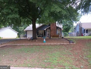 Charming single-story home with brick chimney and a cozy front porch swing, shaded by a large tree at 435 Rosehill Dr, Mcdonough, GA 30253
