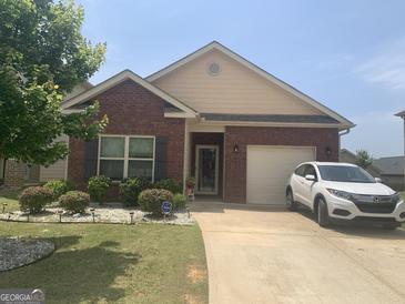 Charming one-story brick home with well-manicured lawn and inviting curb appeal on a sunny day at 2635 Lovejoy Crossing Ln, Hampton, GA 30228