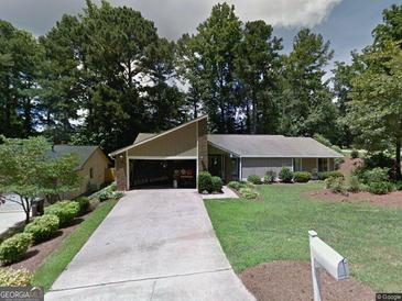 Charming single-story home featuring a well-manicured lawn and attached garage, nestled among mature trees at 100 Lake Forest Dr, Peachtree City, GA 30269