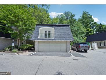 Two-car garage with door to the unit's exterior balcony and black SUV parked to the side on a sunny day at 5490 Chemin De Vie, Sandy Springs, GA 30342