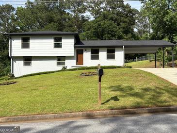 Charming two-story home with a manicured lawn, a carport, and freshly painted exterior at 7340 Chalk Way, Riverdale, GA 30296