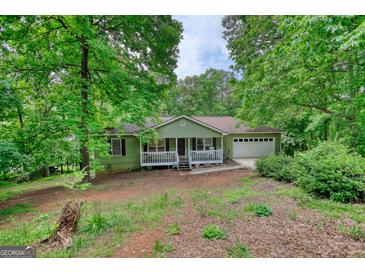 Charming single-story home featuring a quaint front porch and a two-car attached garage nestled among mature trees at 1638 River Trc, Auburn, GA 30011
