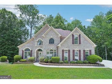 Stunning brick home featuring arched windows, a manicured lawn, and mature trees at 765 Brooks Cir, Stone Mountain, GA 30087
