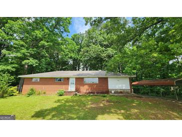 Charming brick ranch-style home with a car port nestled among mature trees in a serene setting at 305 Flat Shoals Church Rd, Stockbridge, GA 30281