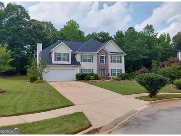 Charming two-story home with a two-car garage, stone accents, manicured lawn, and lovely curb appeal at 75 Trelawney Keep, Covington, GA 30016