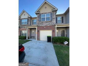 A townhouse featuring mixed exteriors: brick, stone, tan painted siding, with blue shutters and an attached garage at 5257 Carrie Dr, Morrow, GA 30260