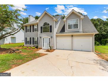 Two-story home showcasing a well-manicured lawn, two-car garage, and a welcoming entrance at 4506 White Rd, Douglasville, GA 30135
