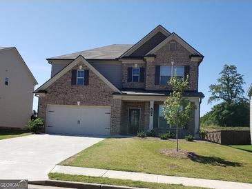 Charming two-story home featuring a brick facade, well-manicured lawn, and a two-car garage, set beneath a clear blue sky at 878 W Union Grove Cir, Auburn, GA 30011
