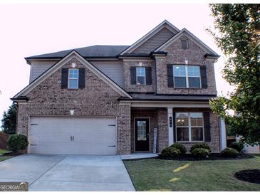 Traditional brick home featuring a two-car garage and well-maintained lawn at 878 W Union Grove Cir, Auburn, GA 30011
