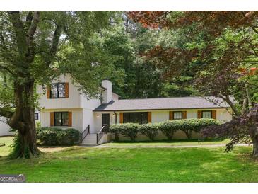 Charming two-story home with a well-manicured lawn, surrounded by lush trees, features black trimmed windows and wood-look shutters at 3308 Quail Sw Run, Marietta, GA 30008