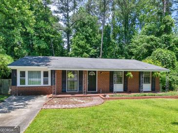 Charming brick ranch with manicured lawn and black shutters, set against a backdrop of lush trees at 1356 Lori Ct, Conley, GA 30288