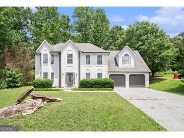 Charming two-story home with white stucco exterior, lush landscaping, and a spacious driveway at 1478 Interlaken Pass, Jonesboro, GA 30238