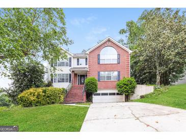 Beautiful two-story brick and white-sided home with a well-manicured lawn, and an attached garage at 182 Spivey Glen Dr, Jonesboro, GA 30236