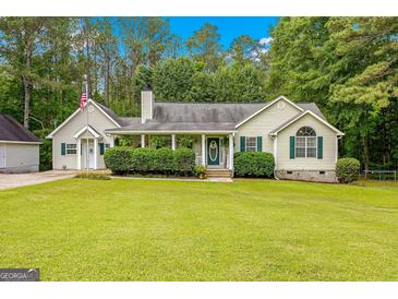Charming one-story home featuring a lush front lawn, cozy porch with decorative details, and traditional architectural elements at 229 Lafayette St, Locust Grove, GA 30248